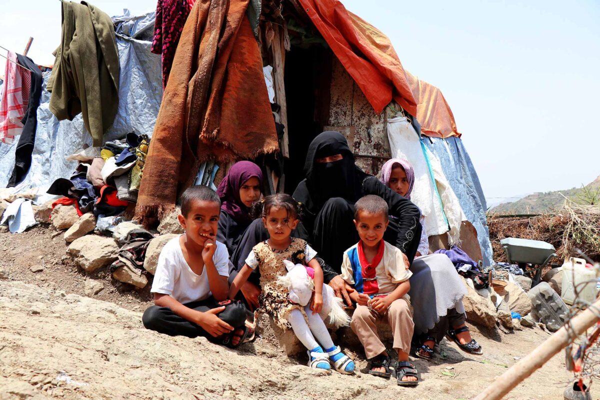 A displaced mother and her 5 children sitting outside their tent