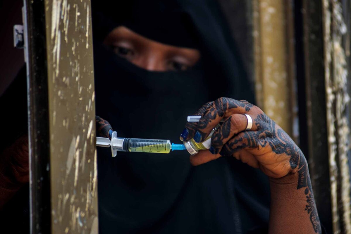 An EU-supported health worker prepares a vaccination shot at a mobile health clinic in a camp housing thousands of displaced Yemenis.